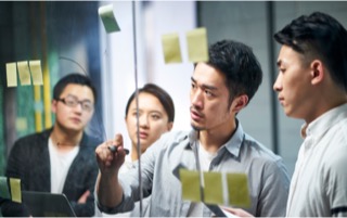 A group of Colleagues are discussing by drawing on a glass window